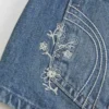 Ultra lavtaljet mini-shorts i mediumvasket denim med blomsterbroderi Ultra lavtaljet mini-shorts i mediumvasket denim med blomsterbroderi